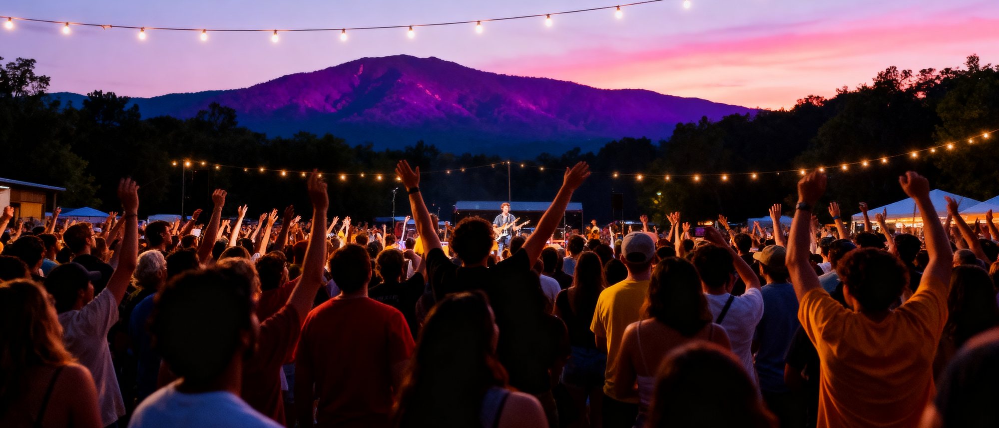 A happy crowd at an outdoor concert with the Blue Ridge mountains glowing at sunset